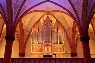 Eine Orgel mit bunter Hintergrundbeleuchtung mit einem Kirchengewölbe