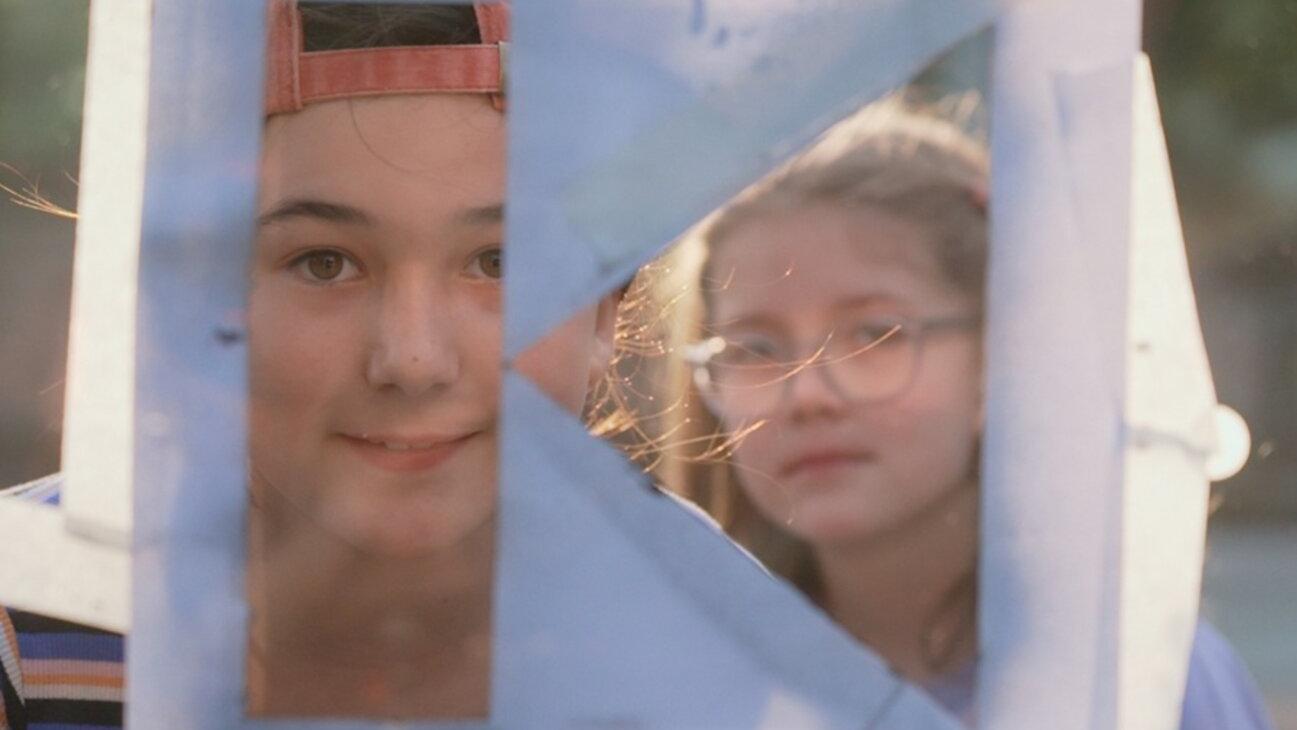 zwei Kinder schauen durch eine Kolping-K Schablone